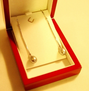 Une paire de boucles d'oreilles en or blanc avec cols de signe et perles grises de culture.